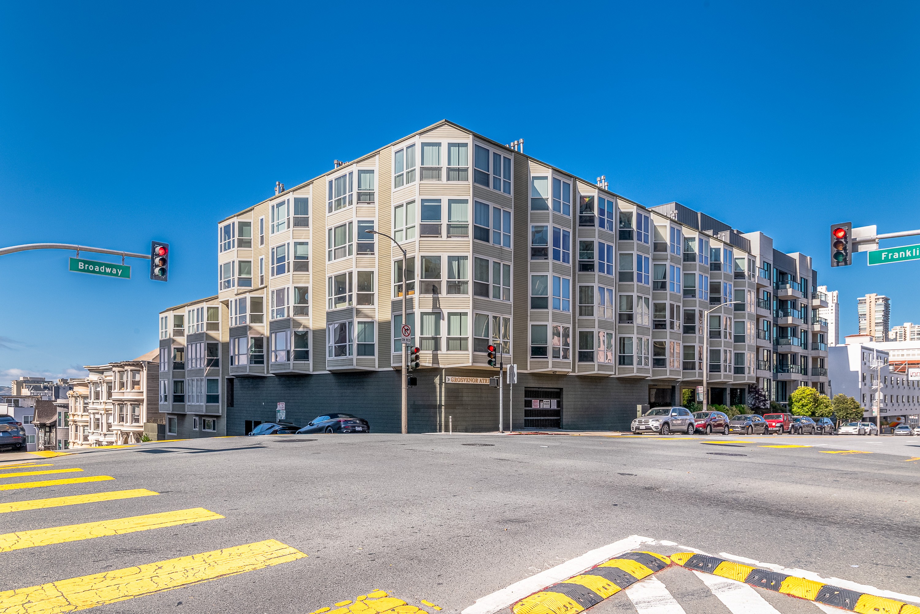 A street view of a multi-story building with a crosswalk in front.